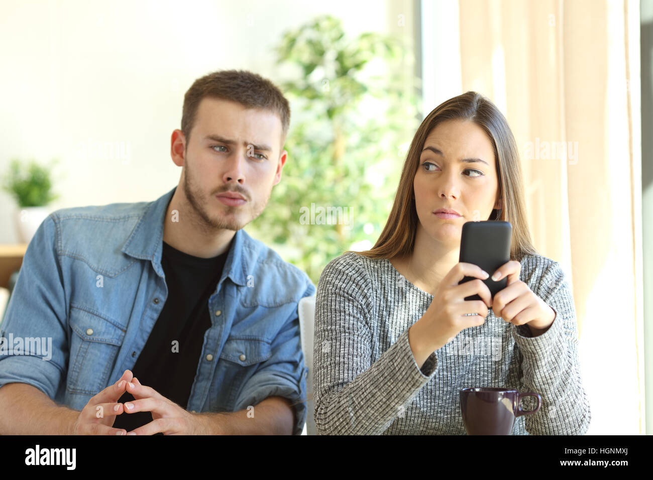 Jealous boyfriend spying his girlfriend watching her phone while image