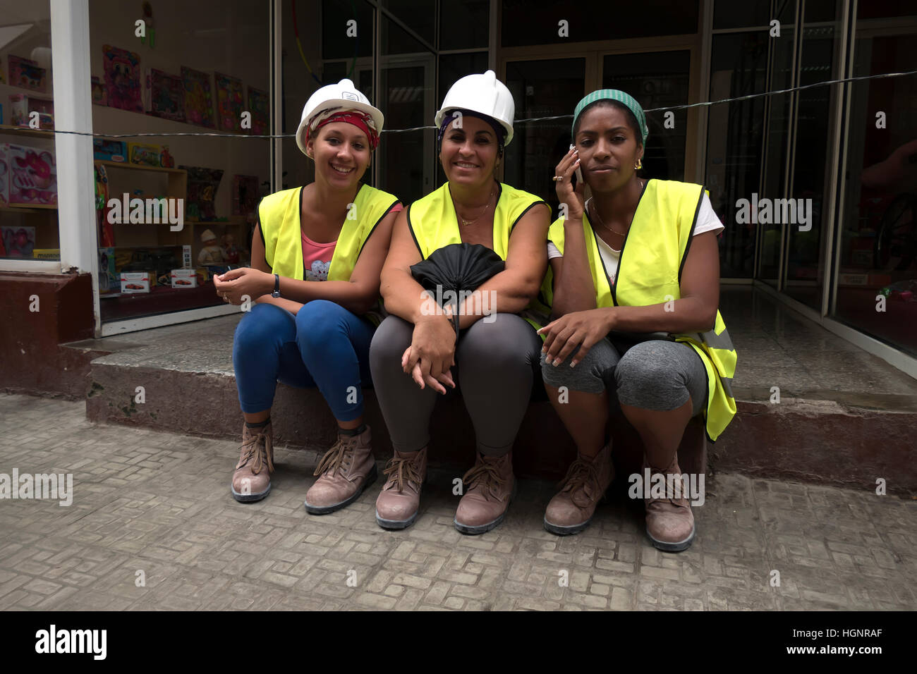 Portrait of happy young Cuban women smiling at camera, people working in construction site, workers in industry. Havana, Cuba Stock Photo