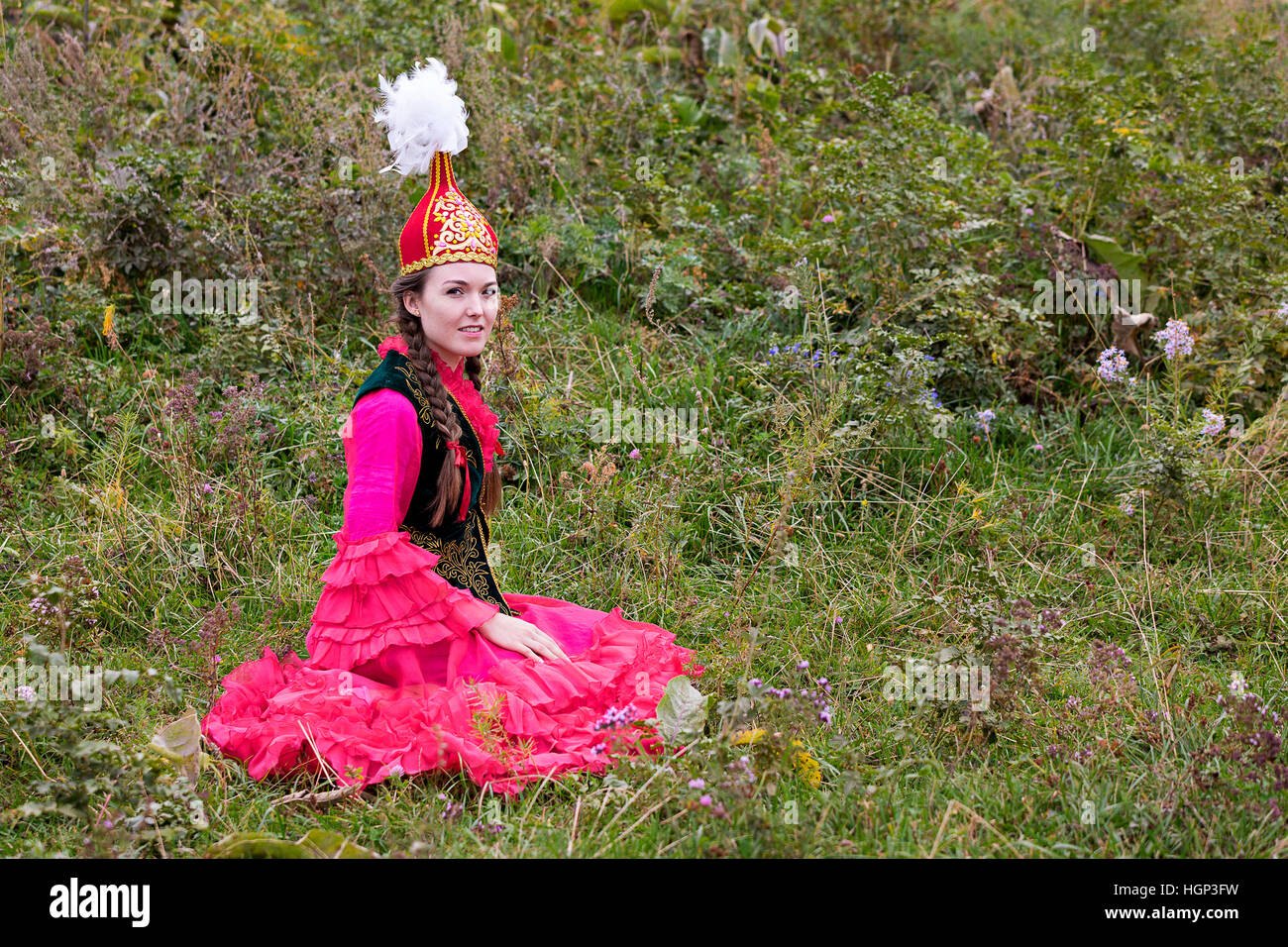 Kazakh woman in national costumes siting in the nature, Kazakhstan Stock Photo