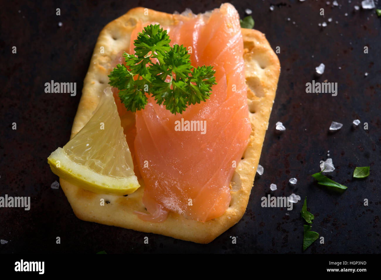Smoked salmon on salted cracker with salt and herbs Stock Photo