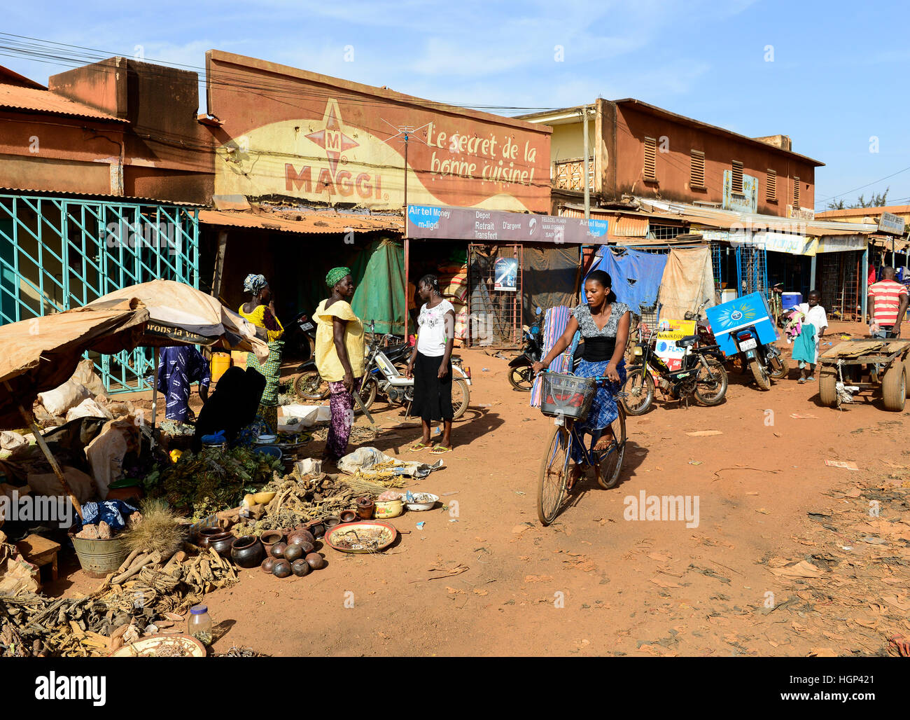 BURKINA FASO , Boulkiemdé Province, Koudougou, shop with Maggi advertisement, Maggi is a brand of swiss Nestle company, in contrast selling of natural roots and herbs on the road Stock Photo