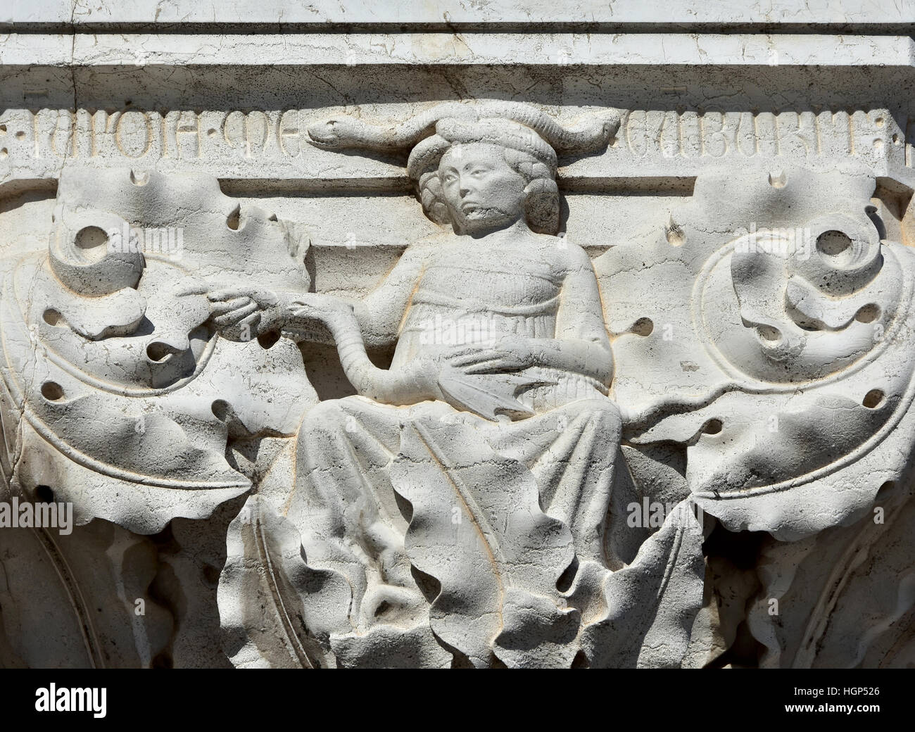Evil witch relief with snake and dragon symbolizes envy vice on doge palace capital in Venice Stock Photo