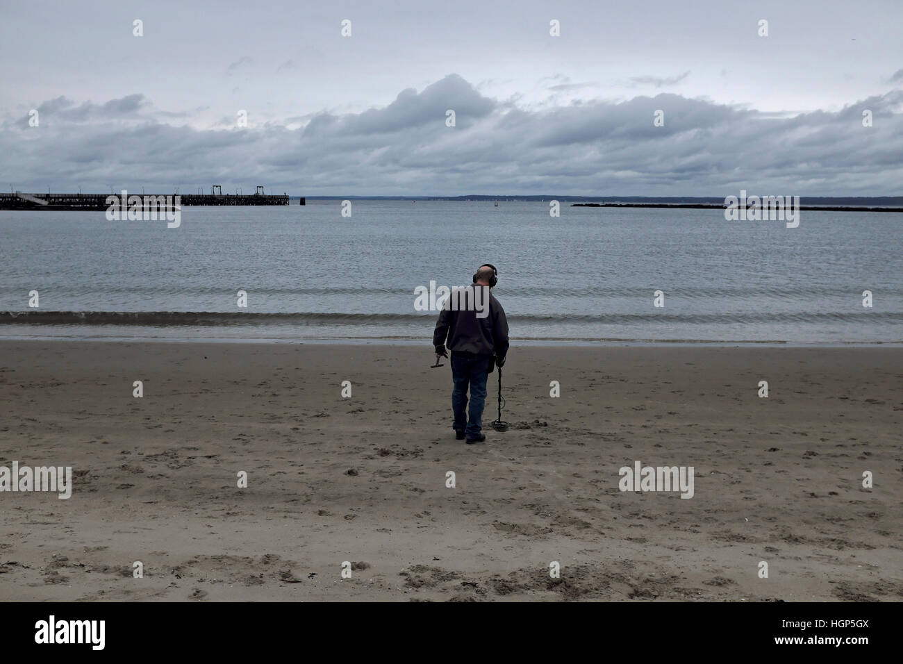 RYE, NY:  A man uses a metal detector on a beach near the Rye Playland Park. 10/9/16 Stock Photo