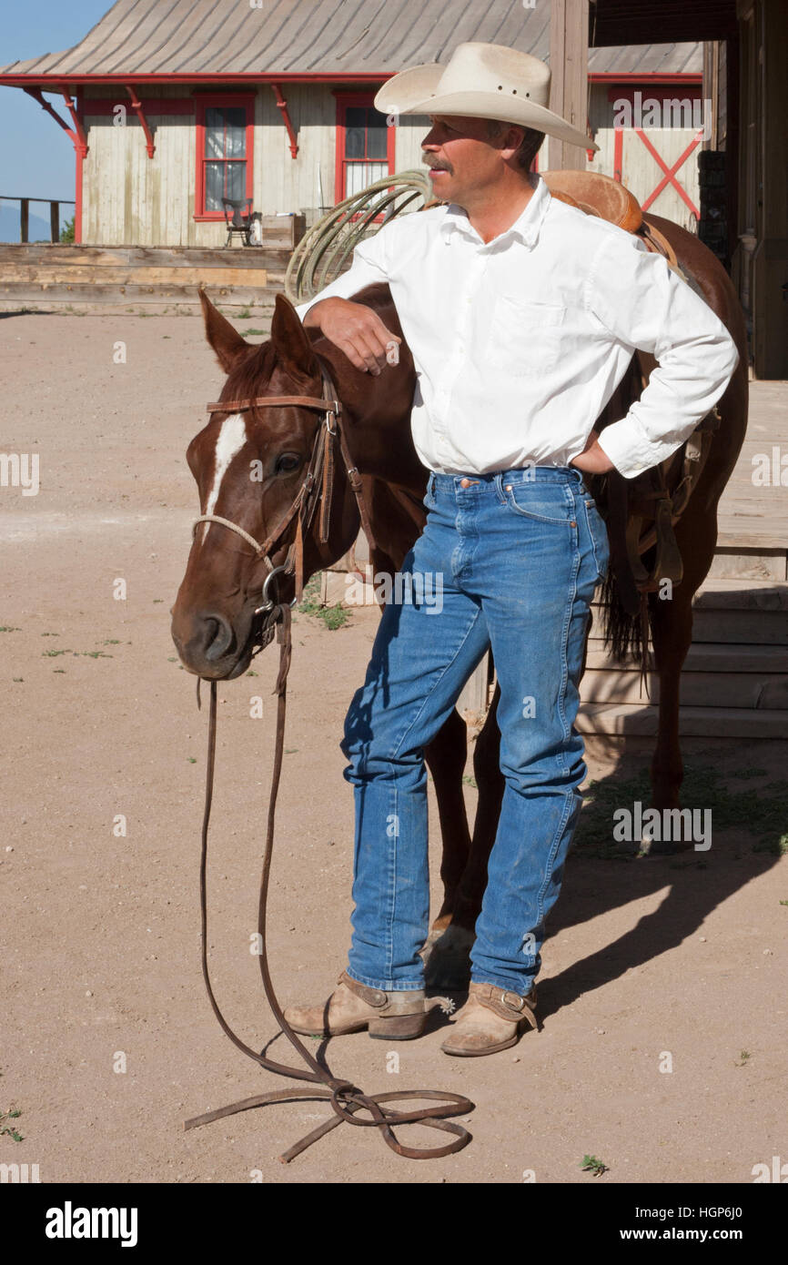 Cowboy with his arm around his horse in old west town Stock Photo