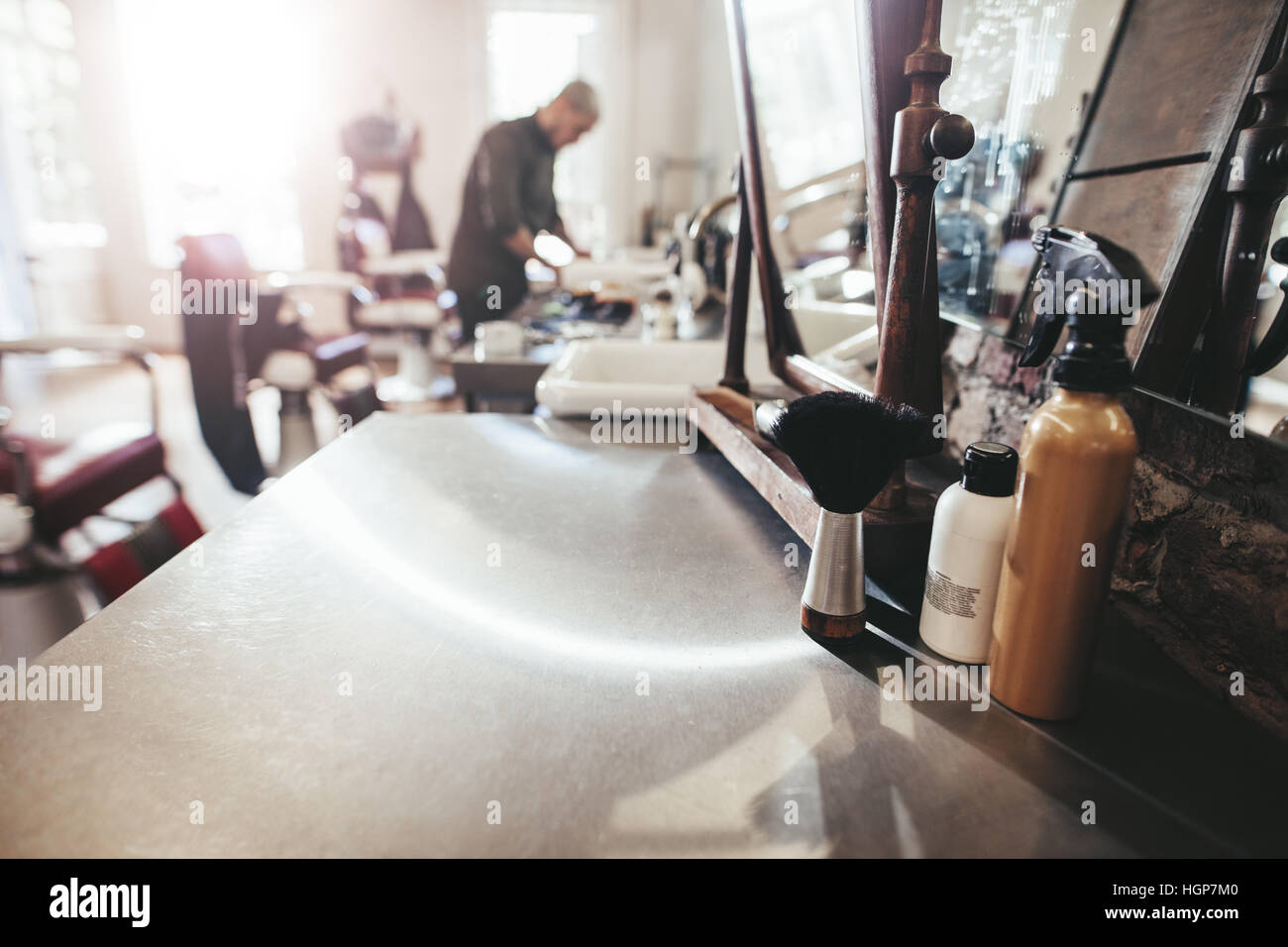 Hairdresser tools on counter with barber in background. Barber shop with hairstyling equipments, Stock Photo