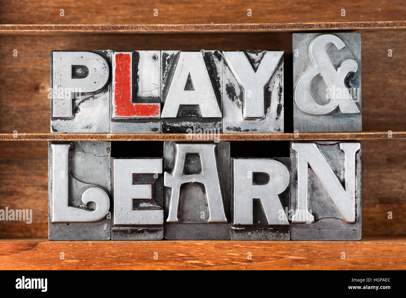 play and learn phrase made from metallic letterpress type on wooden tray Stock Photo