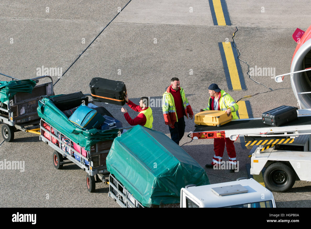 Baggage handlers unloading luggage from an airplane at Dusseldorf airport. Stock Photo