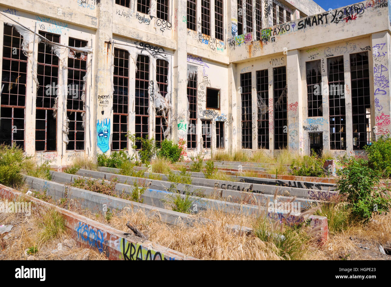 Old abandoned South Fremantle Power Station with youth tagging, broken windows and wild weeds in