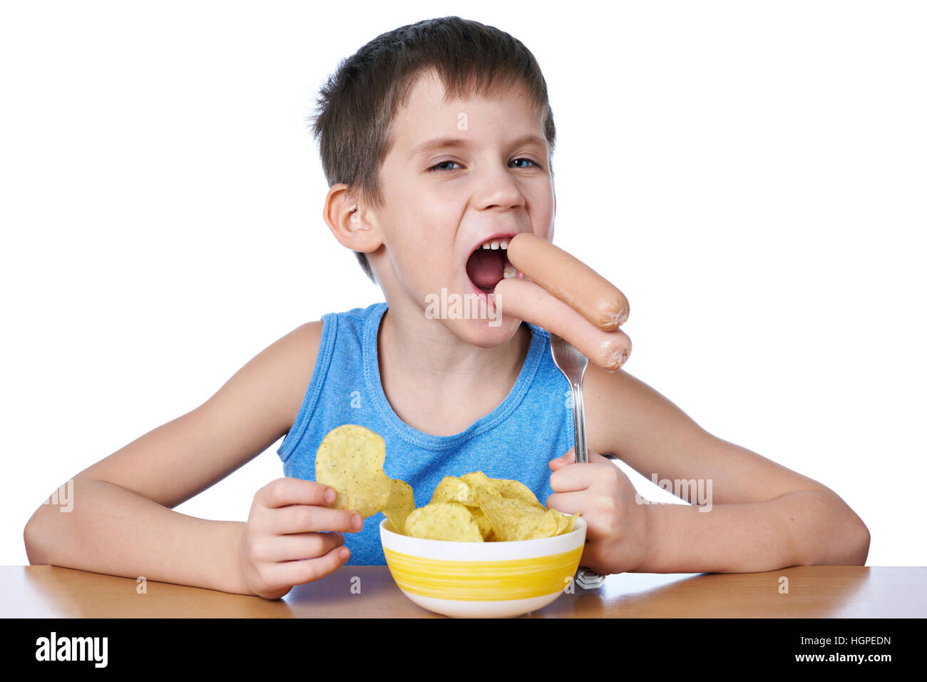 Little boy eating sausages and potato chips isolated white Stock Photo