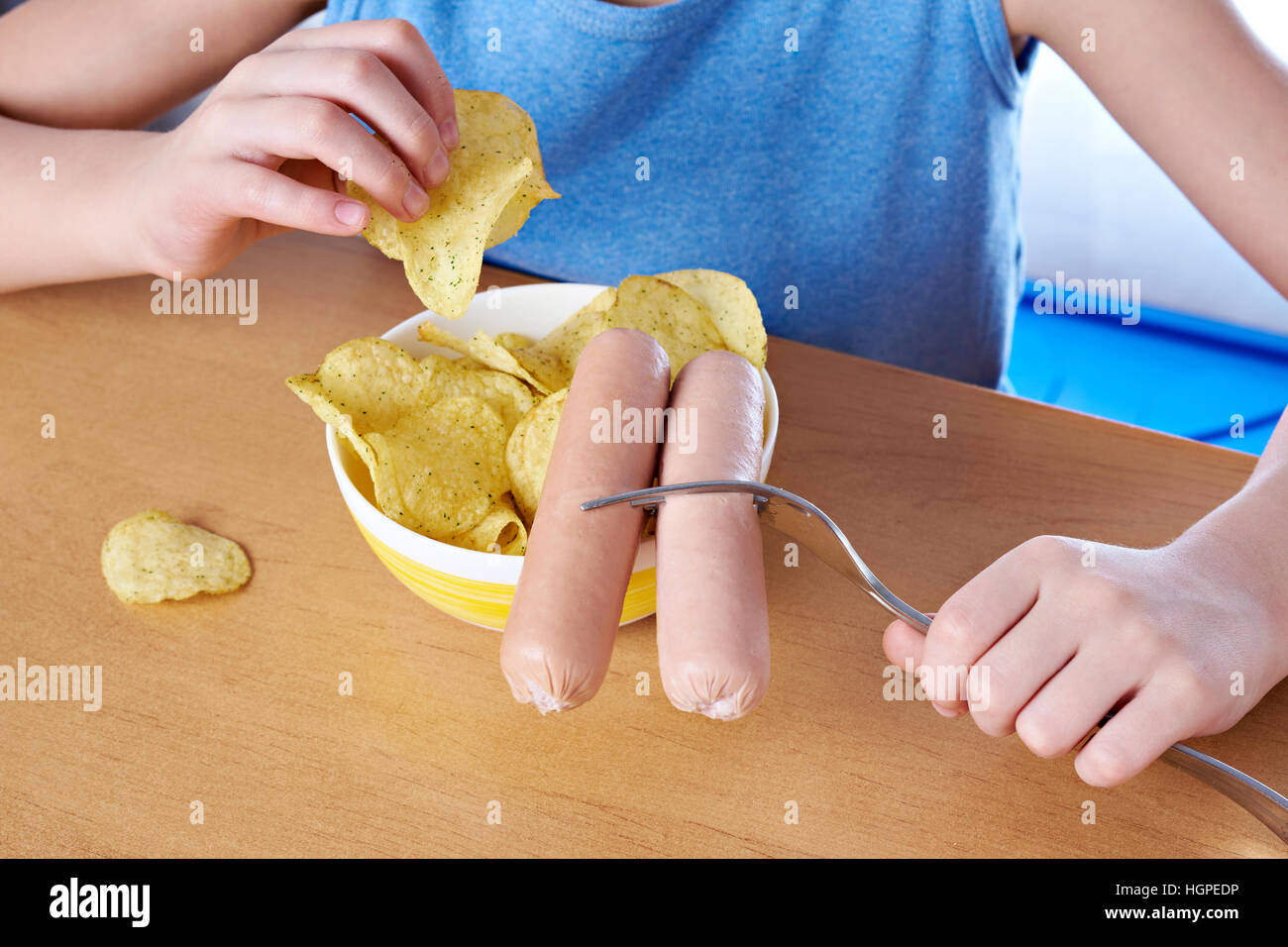 Sausages on a fork and potato chips on the table Stock Photo