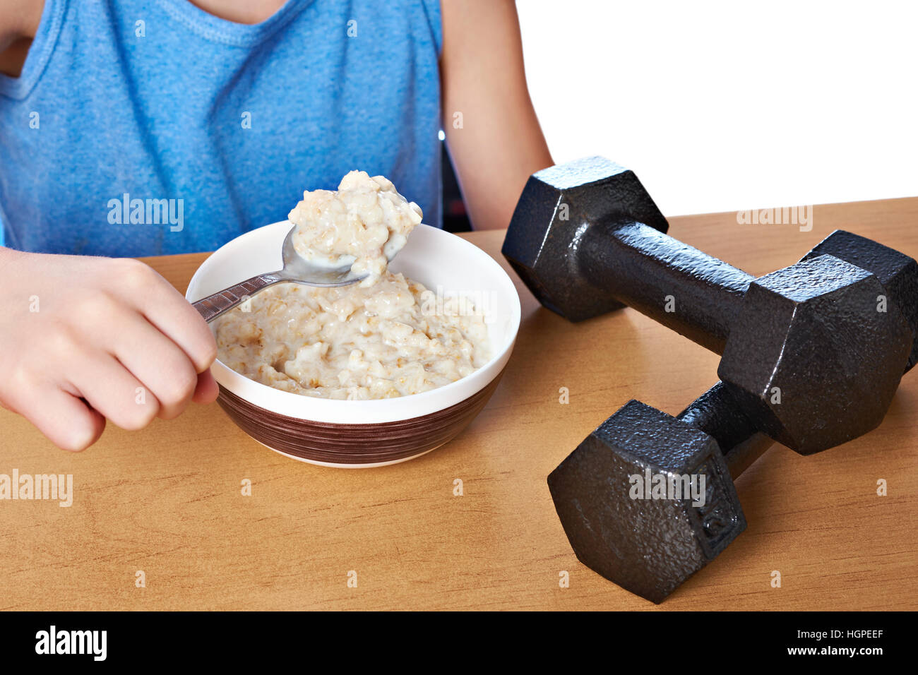 Boy eating porridge and dumbbells as symbols of sports lifestyle Stock Photo