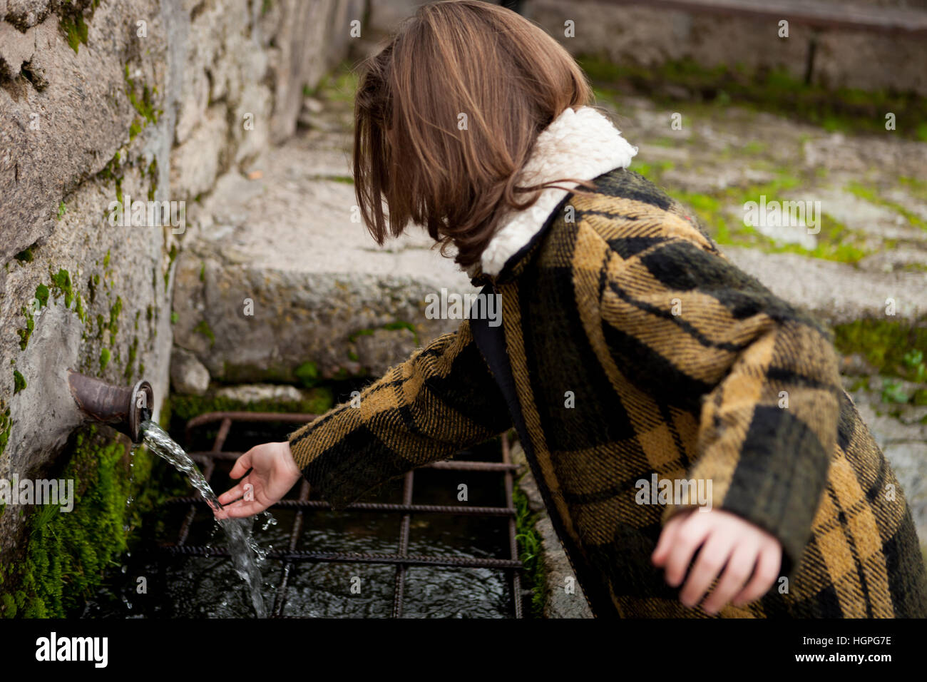 Small girl touching water from a natural fountain Stock Photo