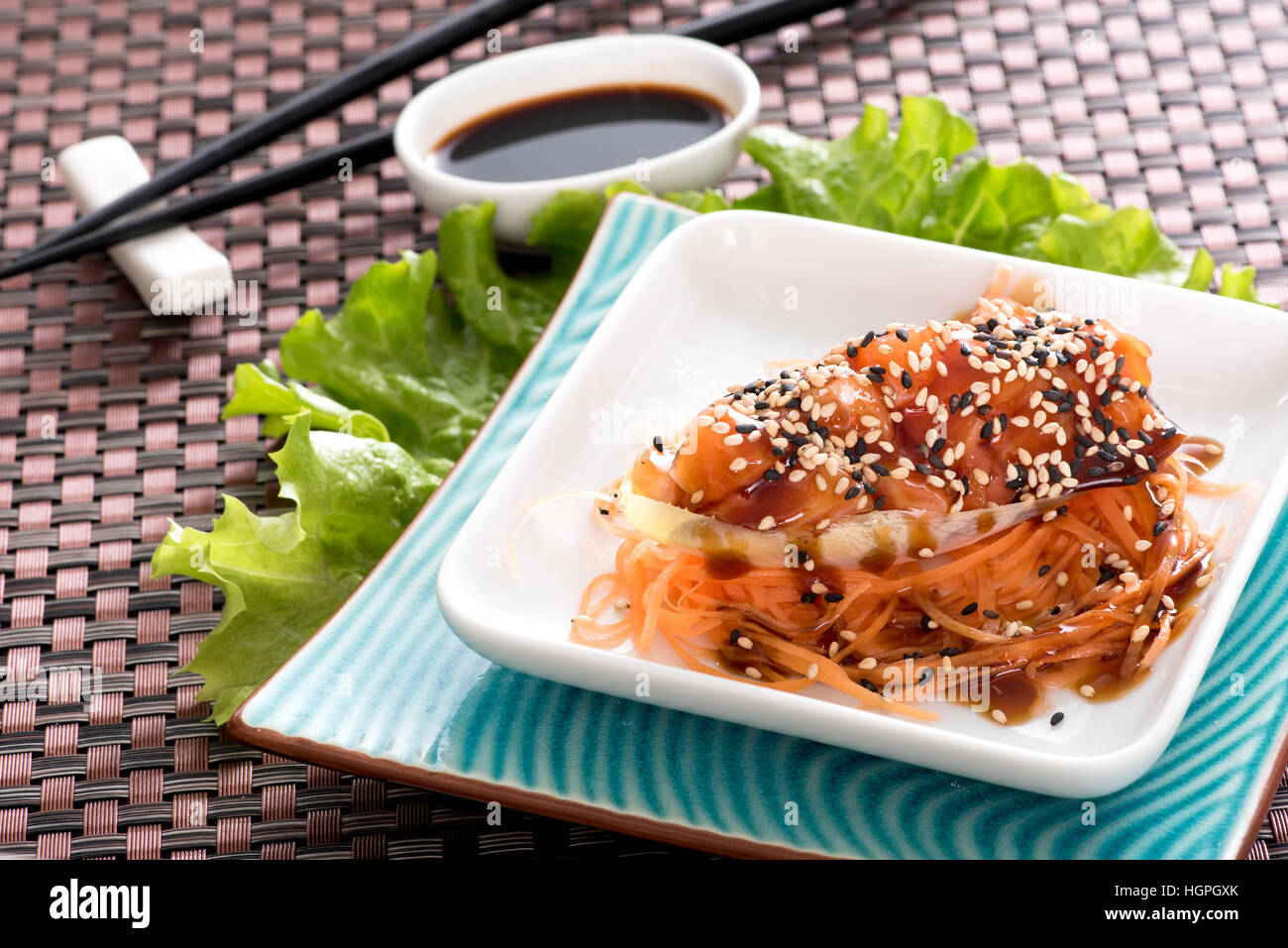 Close up view of white plate with salmon in tartare served with soy sauce and lettuce in asian restaurant Stock Photo