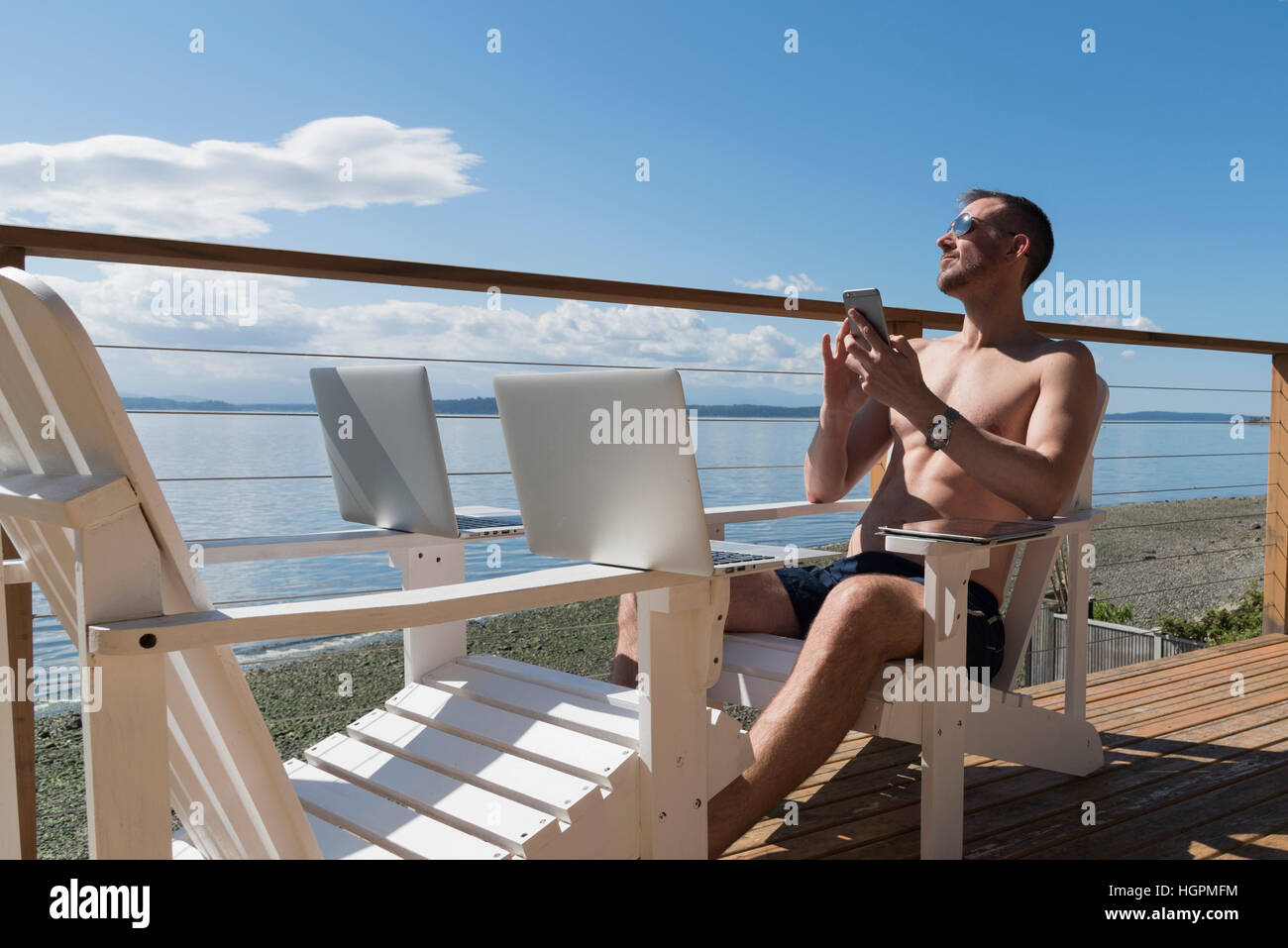 Man working with technology from a seaside deck Stock Photo