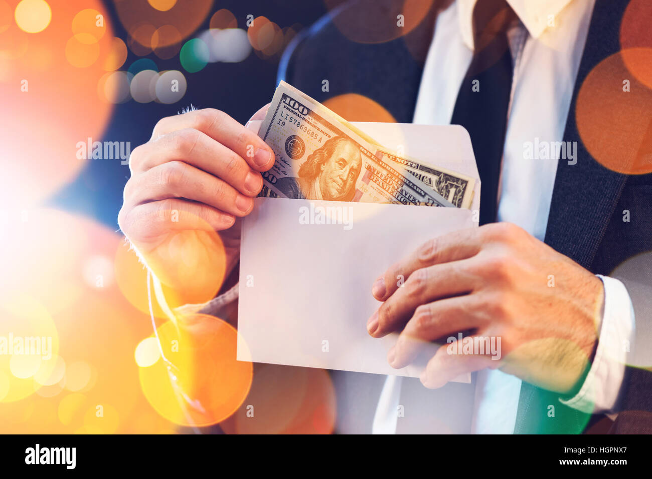 Bribery and corruption concept in business and politics with caucasian businessman taking cash money from envelope on city street at night Stock Photo