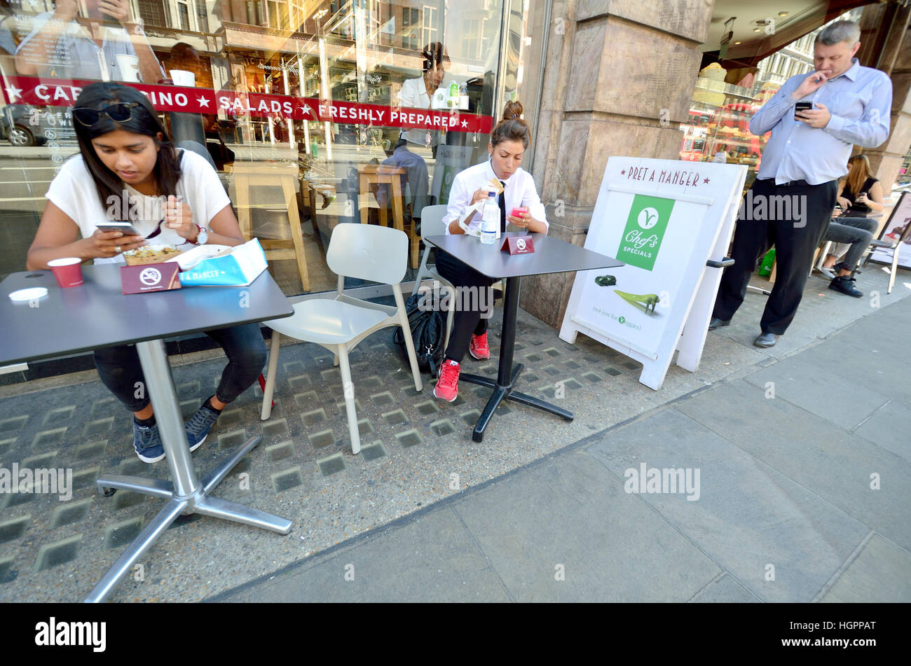 London, England, UK. Pret a Manger shop - three people outside looking at their mobile phones Stock Photo