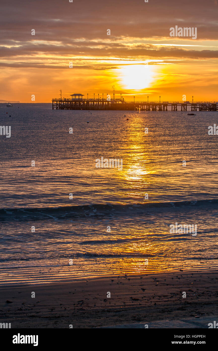 sun rising over silhouette pier and water on beach Stock Photo - Alamy