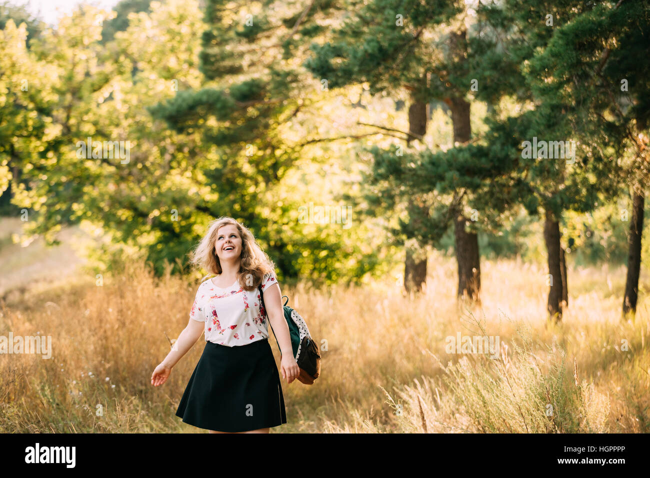 Single Young Pretty Plus Size Caucasian Happy Smiling Laughing Girl Woman In White T-Shirt, Walking With Backpack In Summer Green Forest. Fun Enjoy Ou Stock Photo