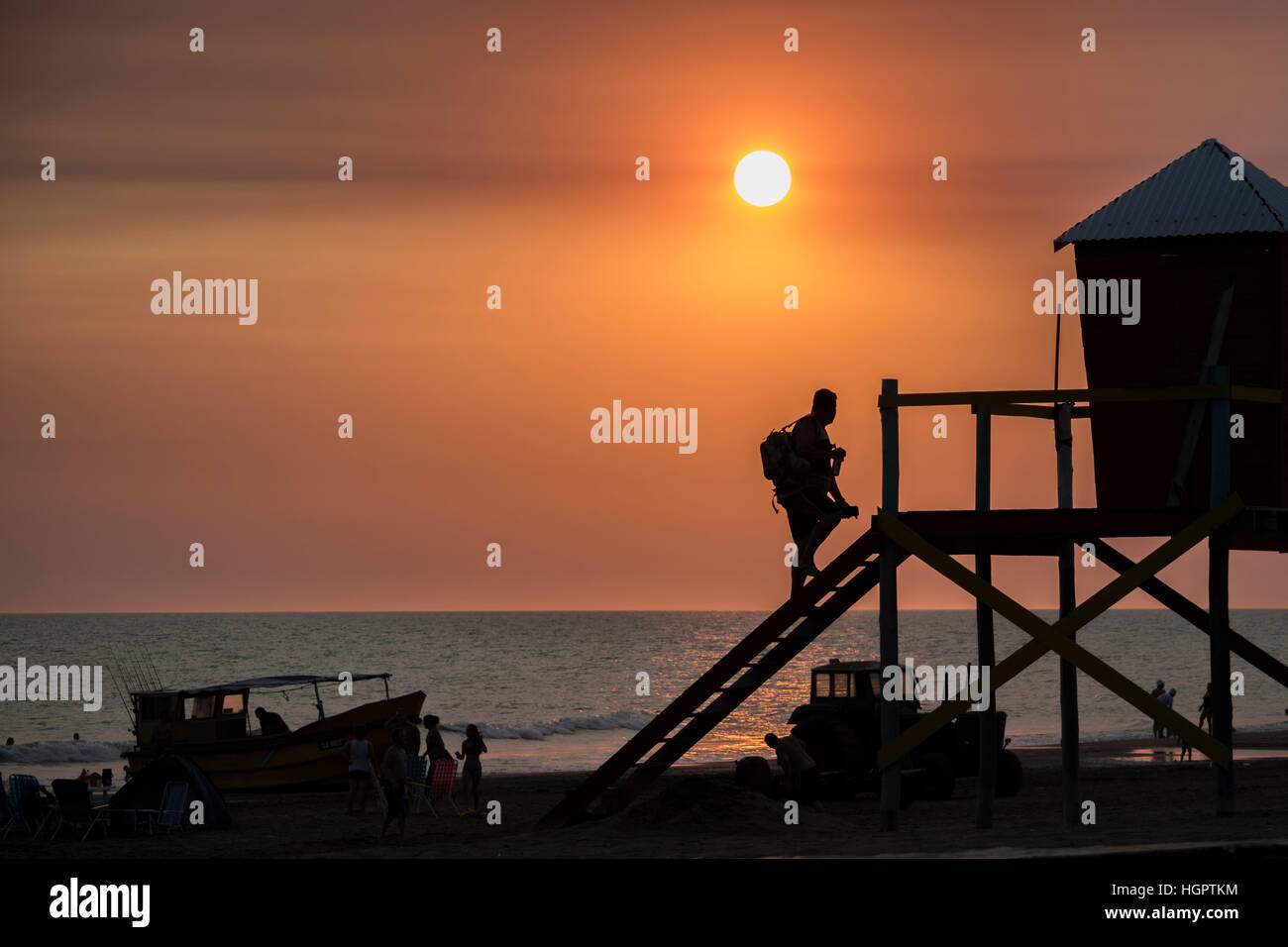 man climbing lifeguard tower at the beach at sunset or sunrise Stock Photo