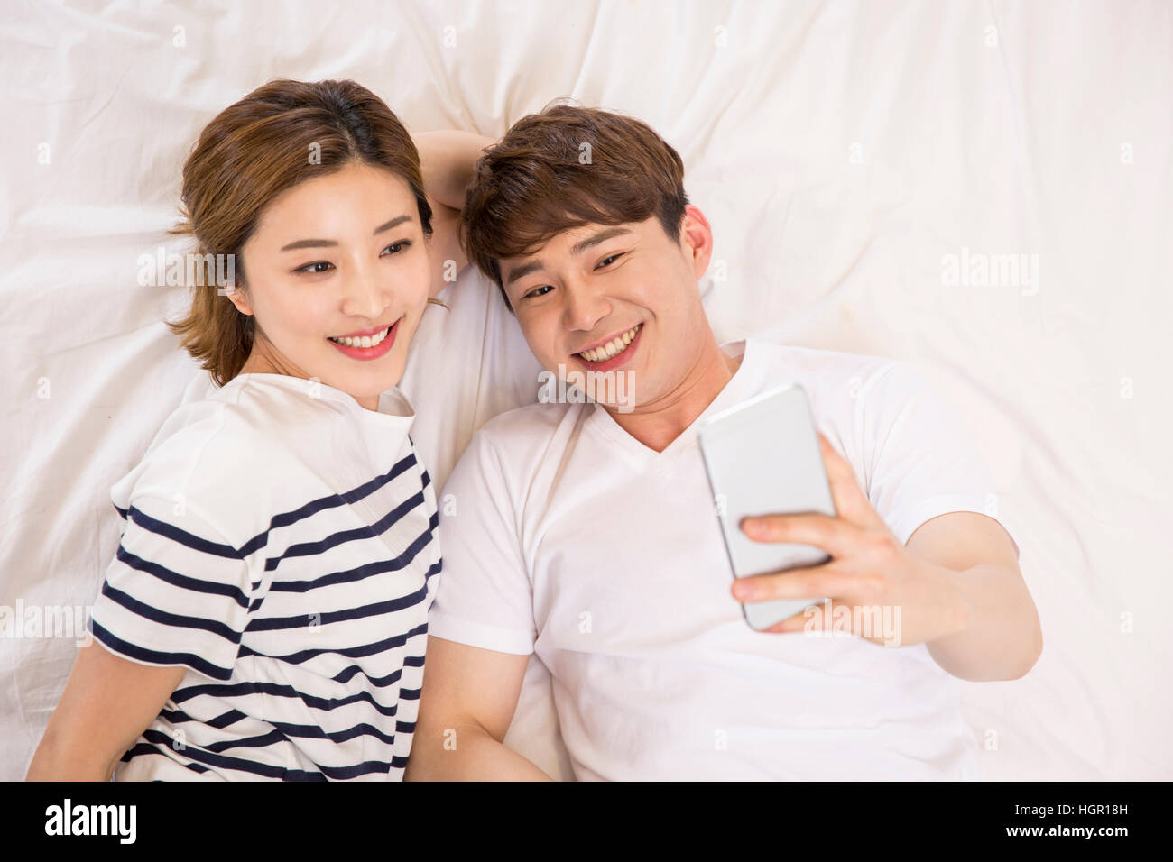 High angle view of young smiling couple lying down on bed Stock Photo ...