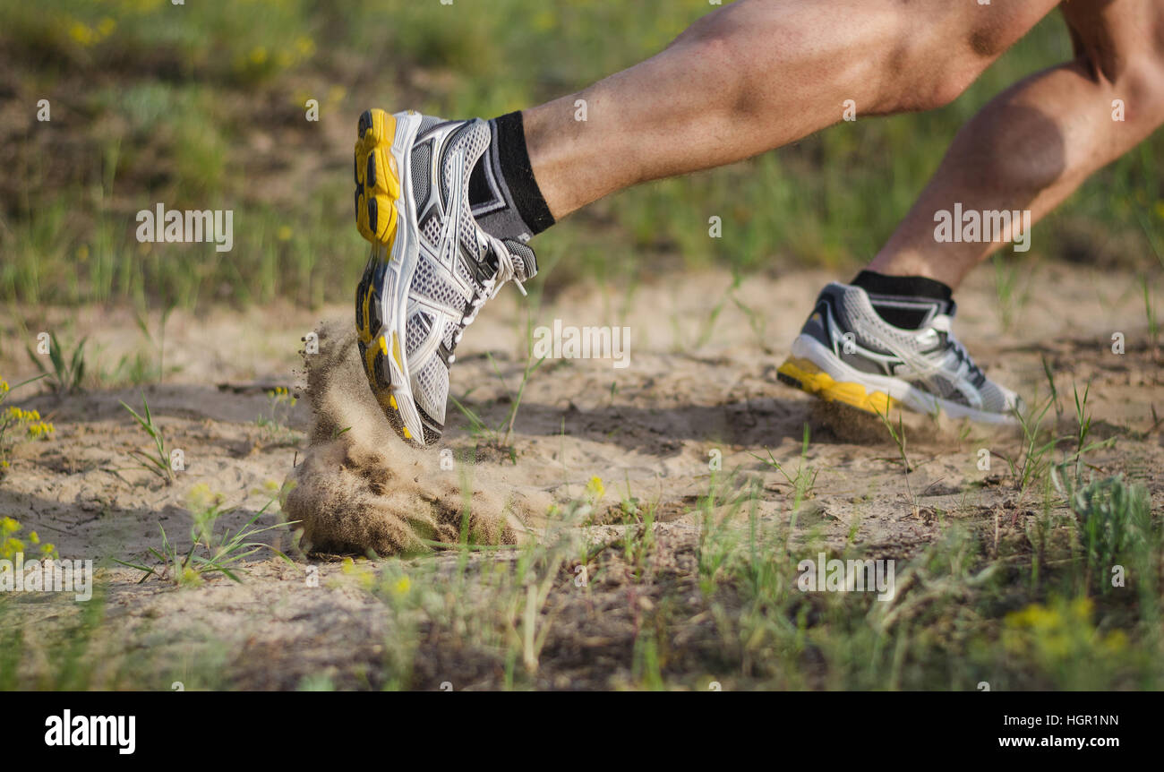 Athlete's foot in sneakers which starts to run. Sand flies under their shoes. Foot motion blur. Stock Photo