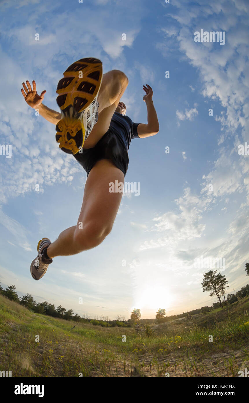 Young athlete jumps while running. Close-up of shoe sole, bottom view. Legs blurred in motion. Stock Photo