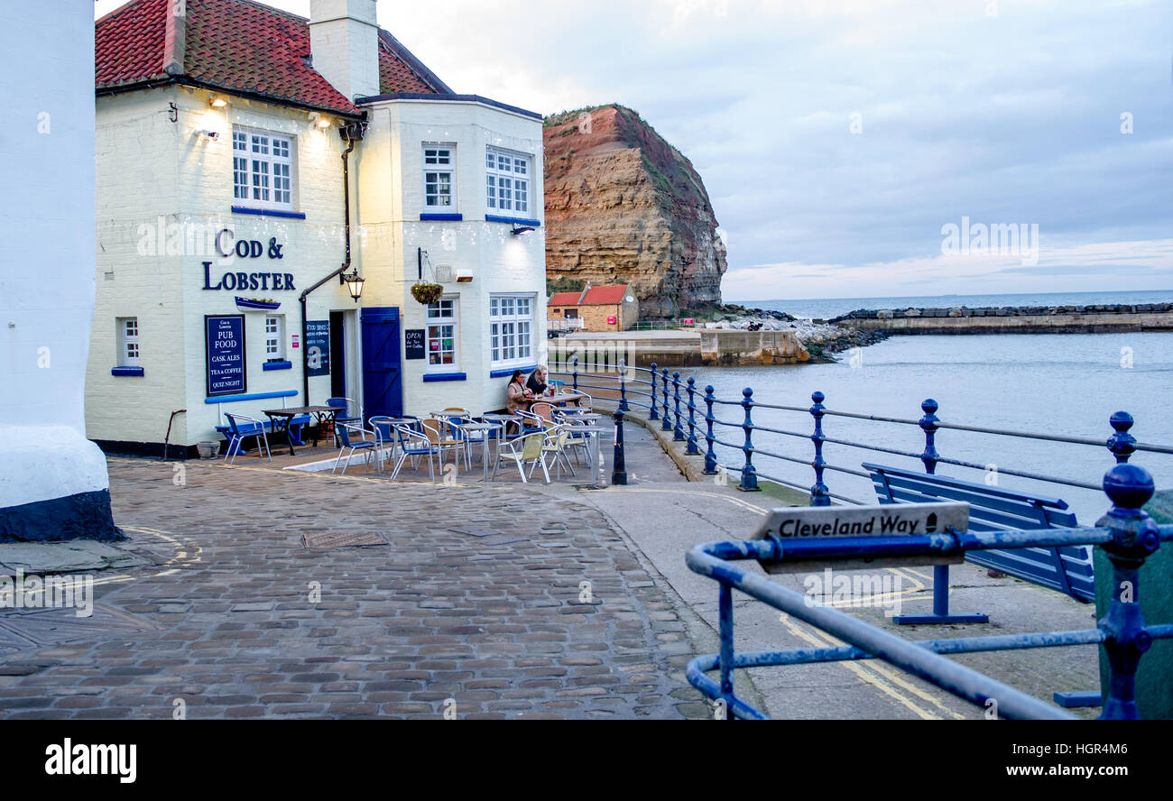 Two women eating a meal outside the Cod and Lobster pub at Staithes harbour, North Yorkshire, England U.K. Stock Photo