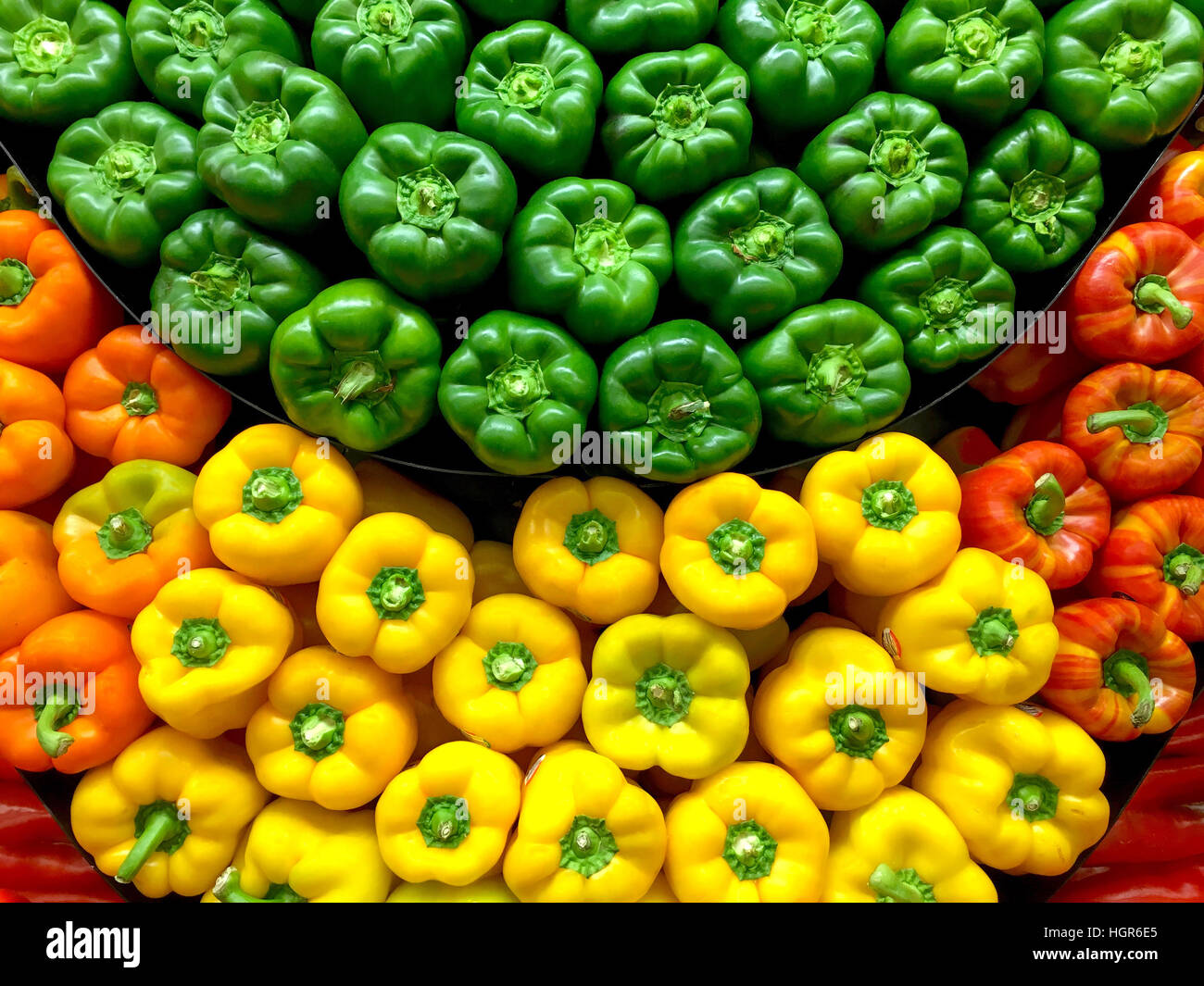 Green, yellow and red bell peppers stacked at the market Stock Photo ...