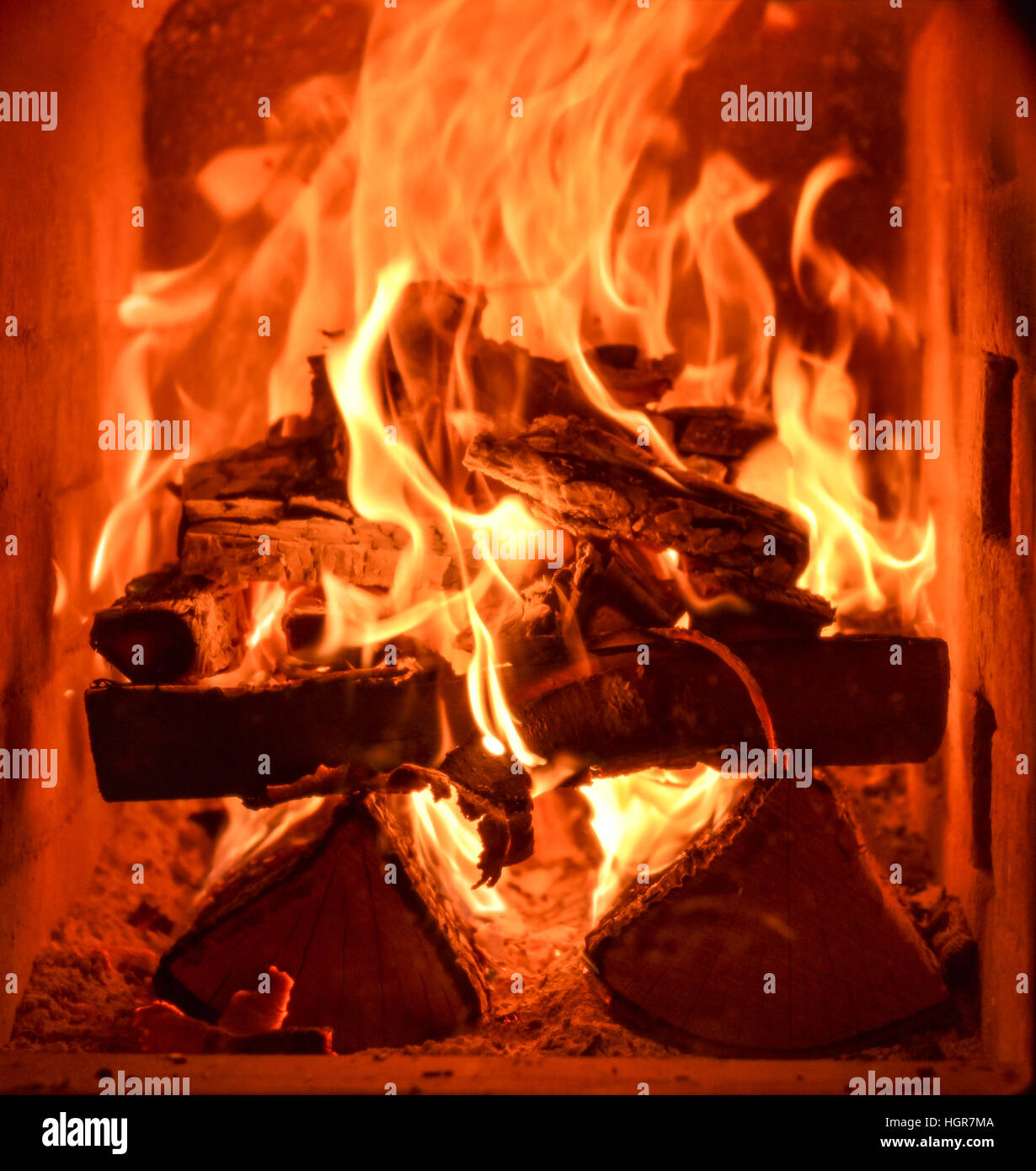 Closeup of the inside of home traditional fireplace running on natural hard wood with flames and heat. Stock Photo