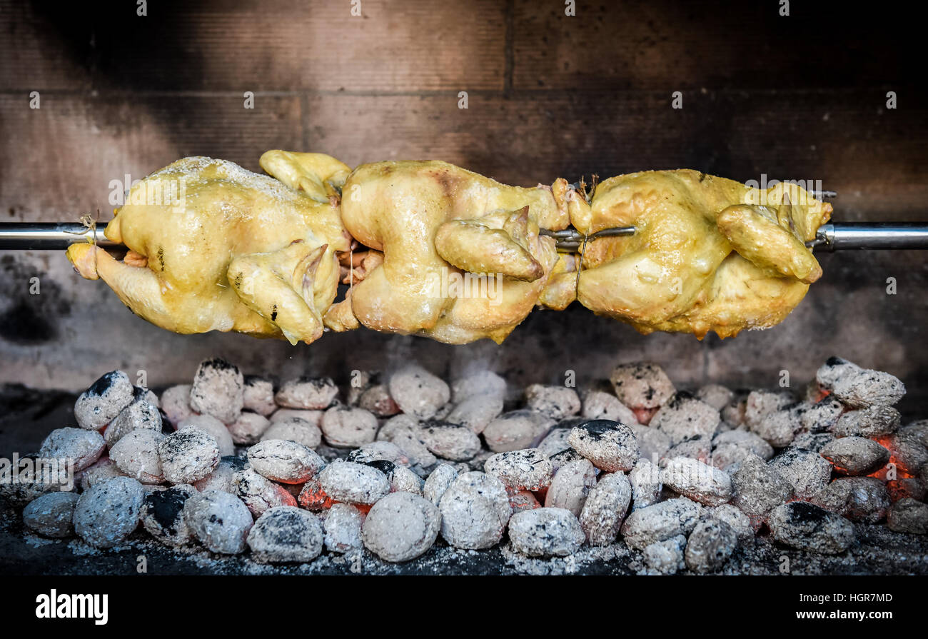 Cooking raw rotisserie chicken on the grill with Charcoal and Briquettes in the professional