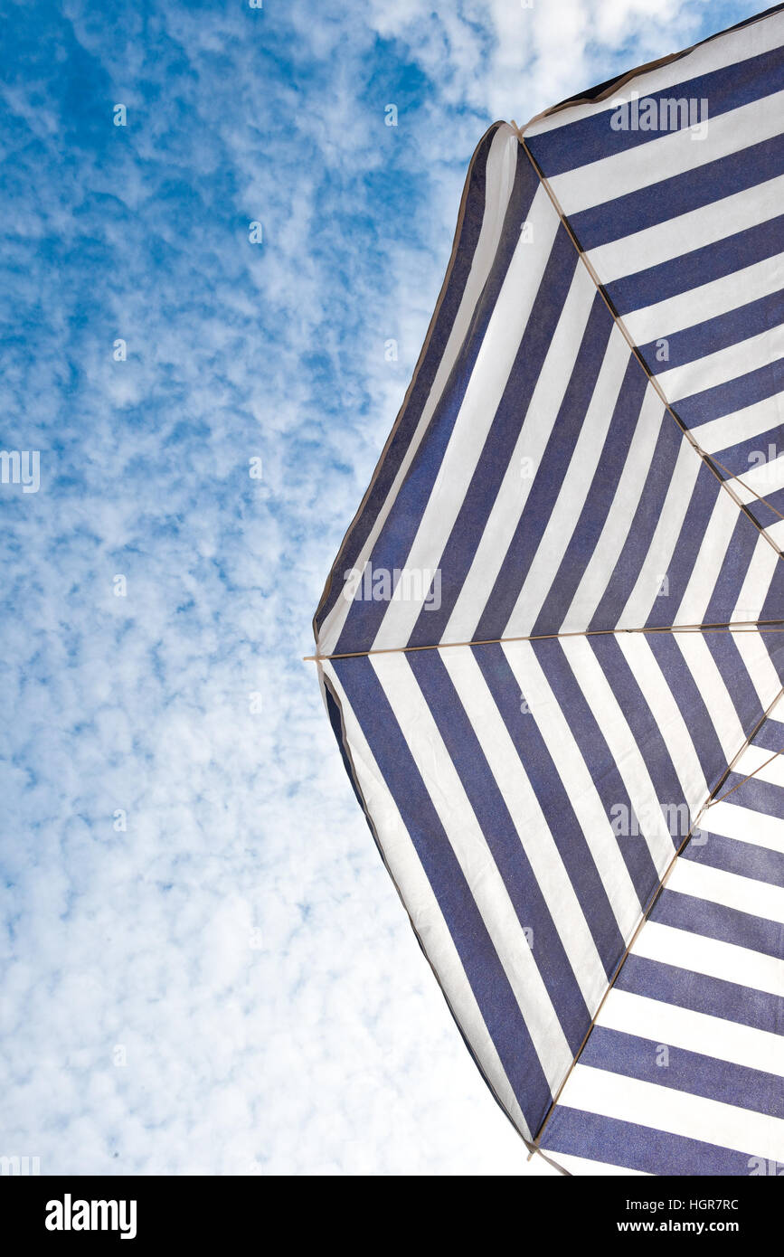 Blue and white sun protection beach umbrella and blue sky with clouds
