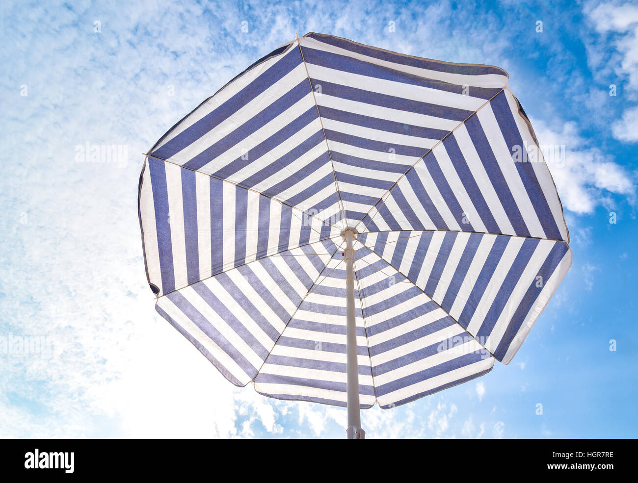 Blue and white sun protection beach umbrella and blue sky with clouds