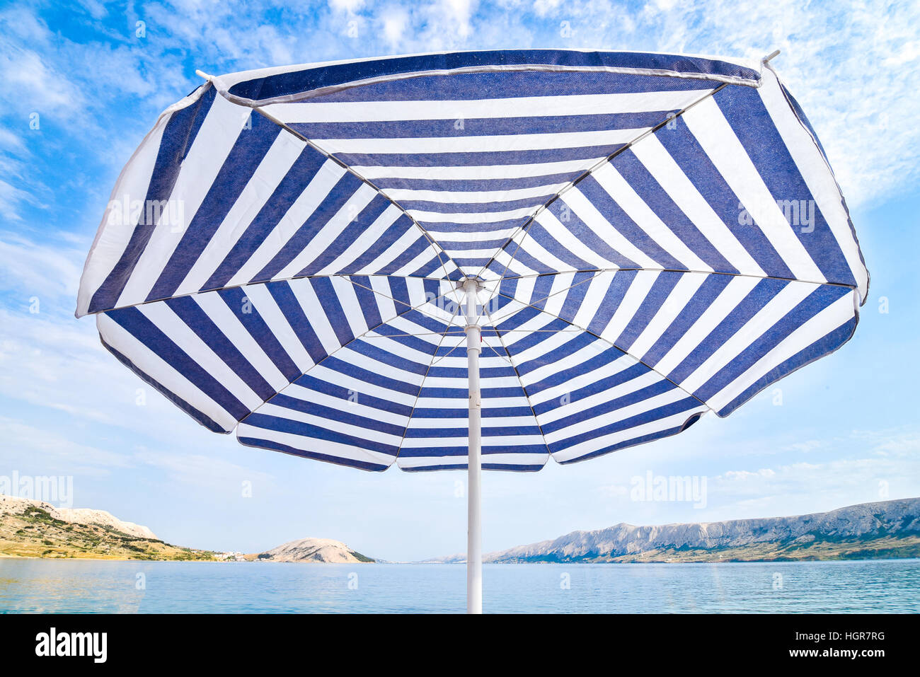 Blue and white sun protection beach umbrella and blue sky with clouds