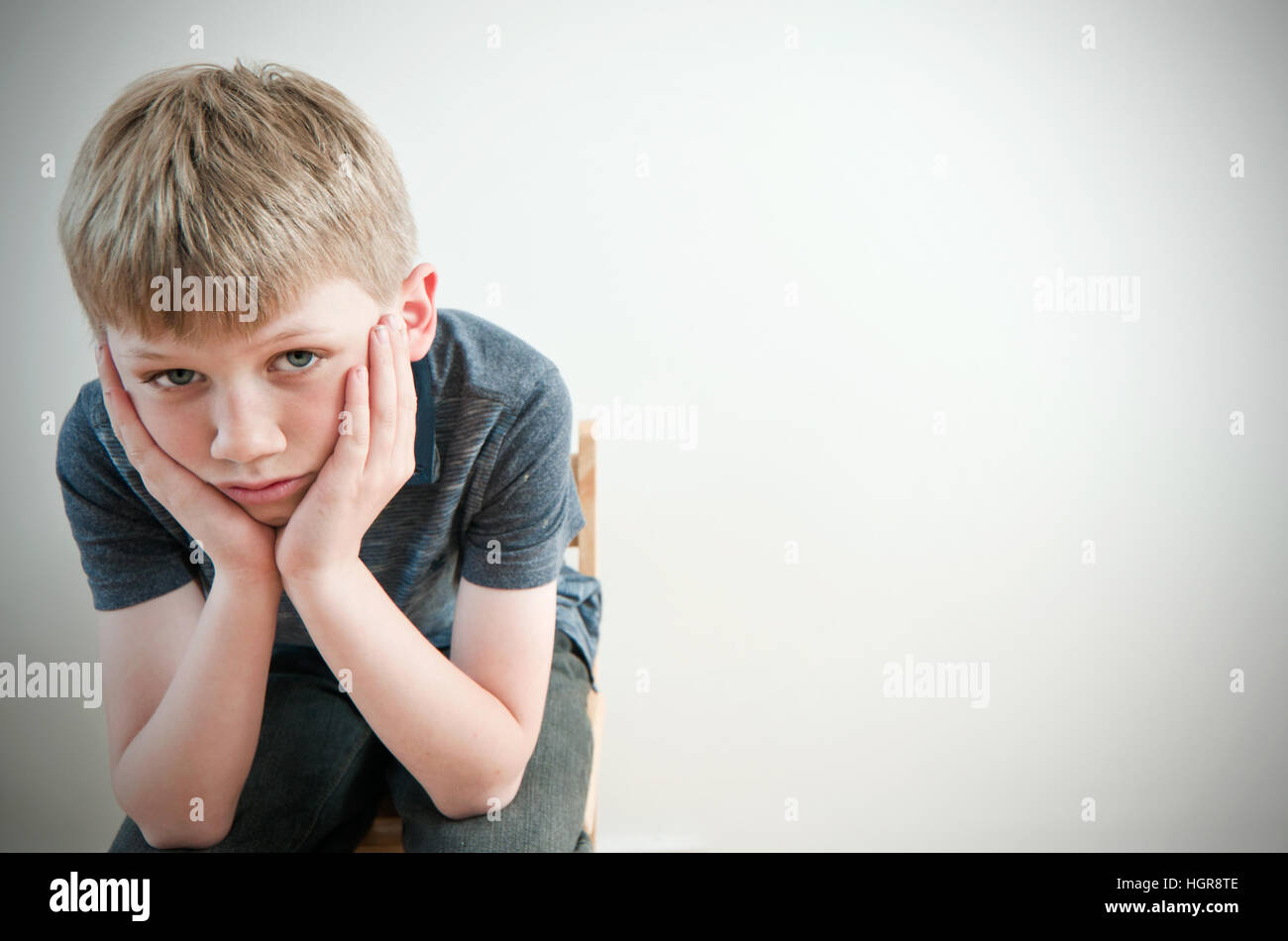 A sad and dejected young child against a plain background with copy space to the right Stock Photo