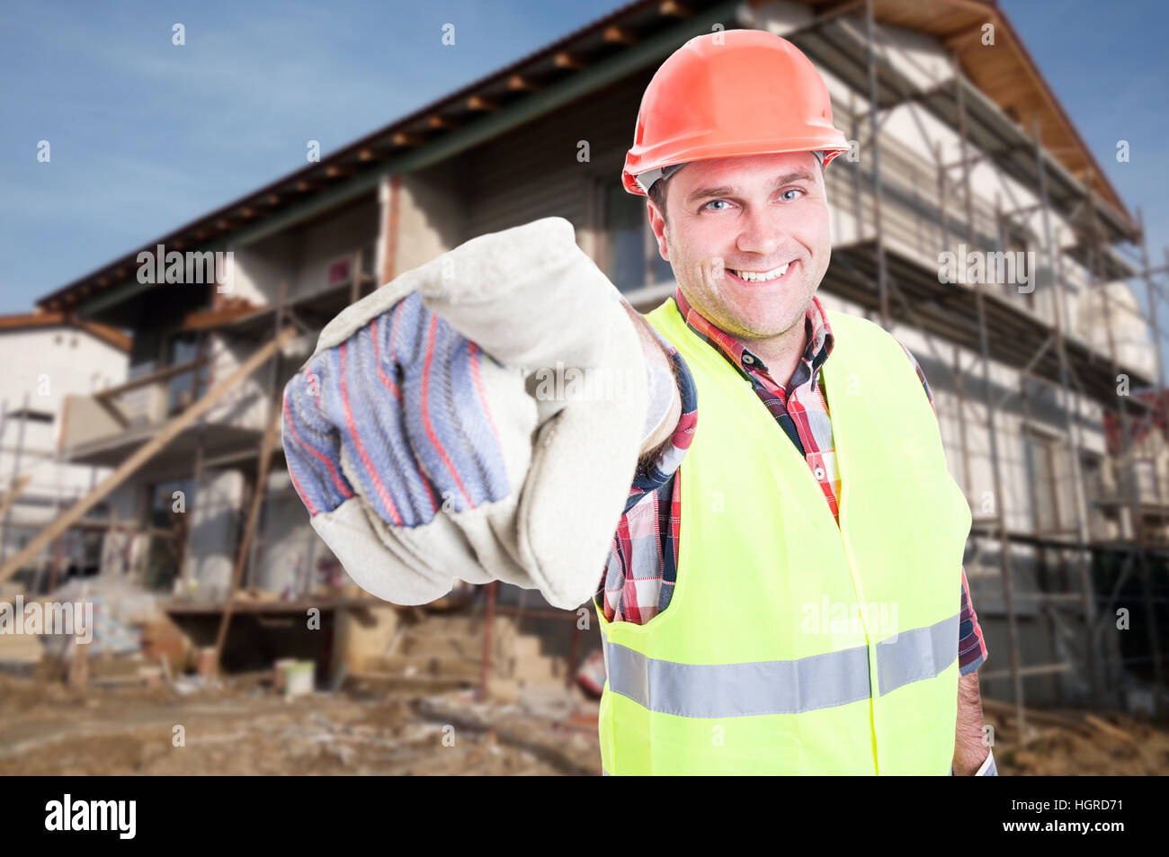 Attractive male builder pointing finger at you and smiling with house ...