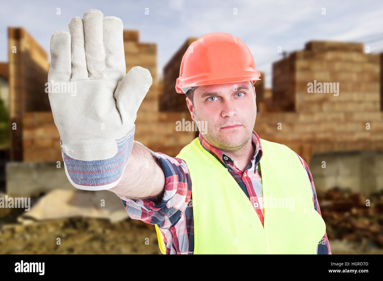 Portrait of male builder rising hand and doing stop sign in front of ...