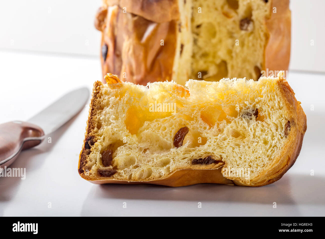 Slice of panettone with knife on white table Stock Photo