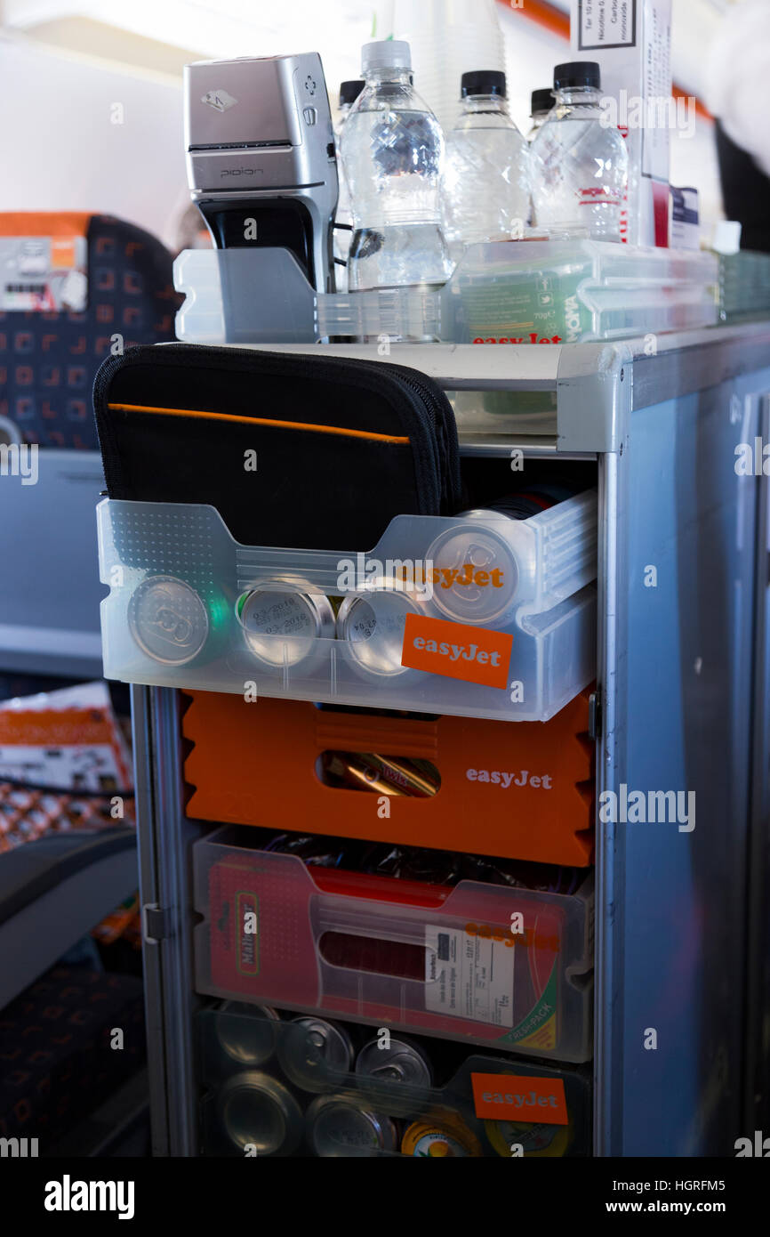 A trolley cart during an Easyjet flight. Cabin crew / air stewardess serves drinks / snacks to passengers, & takes money payment Stock Photo
