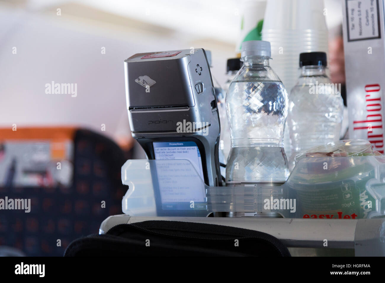 Money payment terminal device & trolley cart. Cabin crew air take passenger credit card payment for drinks snacks Easyjet flight Stock Photo