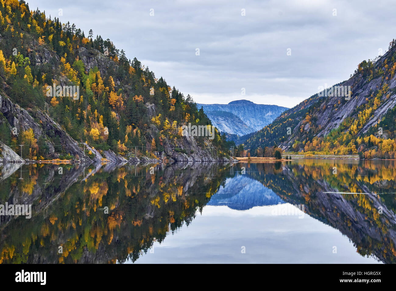 Completely calm waters on lake Flaani, between mountain sides covered in autumn colored trees, near route 9 in southern Norway Stock Photo