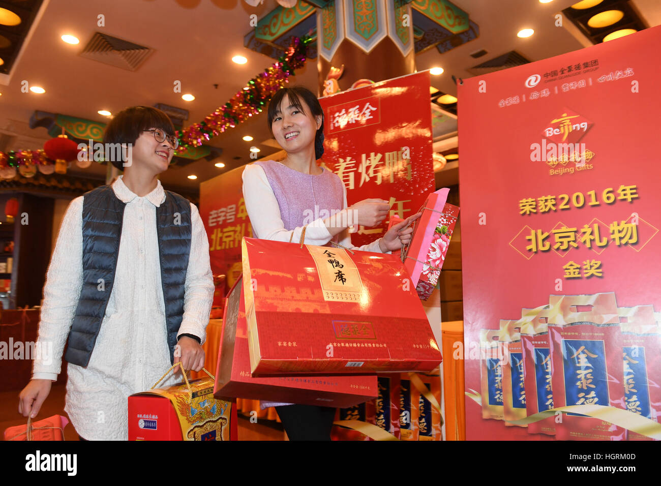 Beijing, China. 12th Jan, 2017. Two customers leave after purchasing goods for Chinese Lunar New Year at the Hepingmen Branch of Quanjude Beijing Roast Duck Restaurant in Beijing, capital of China, Jan. 12, 2017. As the Chinese Lunar New Year is approaching, Quanjude Group launched over 40 kinds of products to fulfill the customers' needs of festival shopping. The Chinese Lunar New Year will fall on Jan. 28 this year. © Li Jundong/Xinhua/Alamy Live News Stock Photo