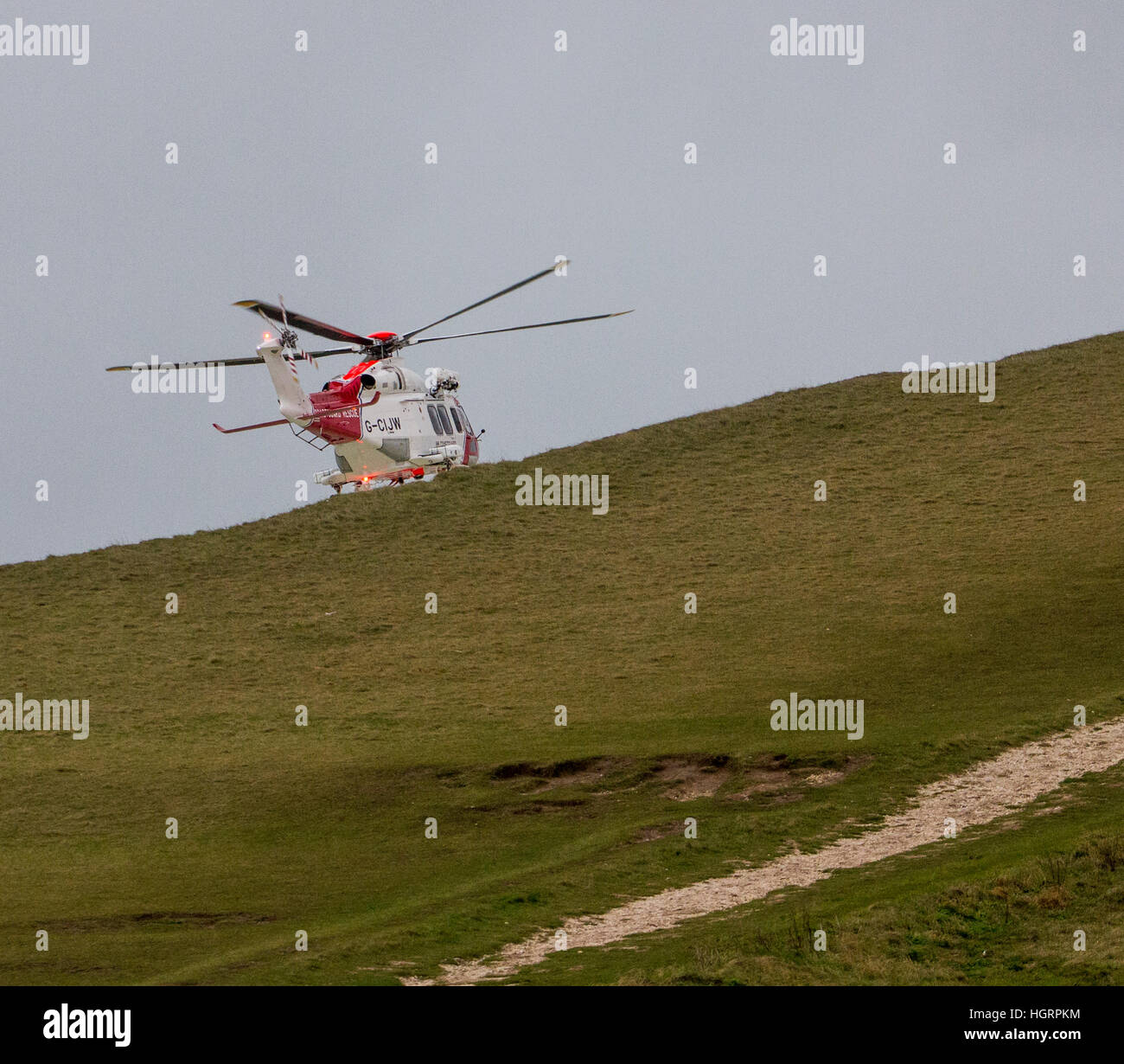 Beachy Head, East Sussex, United Kingdom. 12th Jan, 2017. A Coast Guard Helicopter assists in the search for a person believed to have fallen from the cliffs near Belle Toute lighthouse, after an abandoned motorcycle and clothing were found. A body was later recovered from the beach below at this notorious suicide spot on the South coast of England.In May 2017 the coroner, Alan Cruze found that the victim Ashleigh Connor Martin had taken his own life. Credit: © Alan Fraser/Alamy Live News Stock Photo