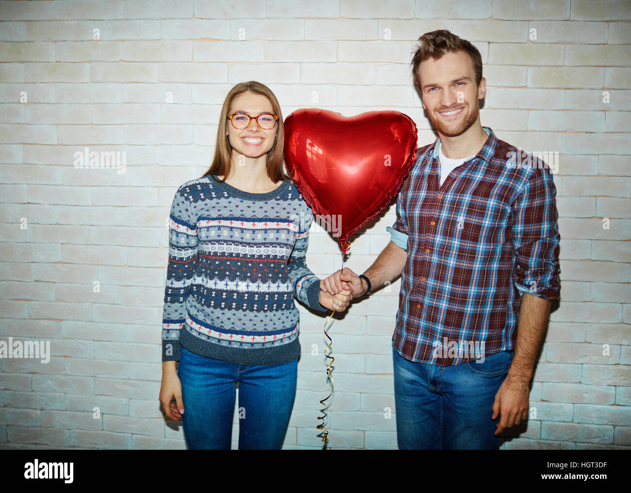 Romantic young couple holding red balloon in form of heart Stock Photo ...