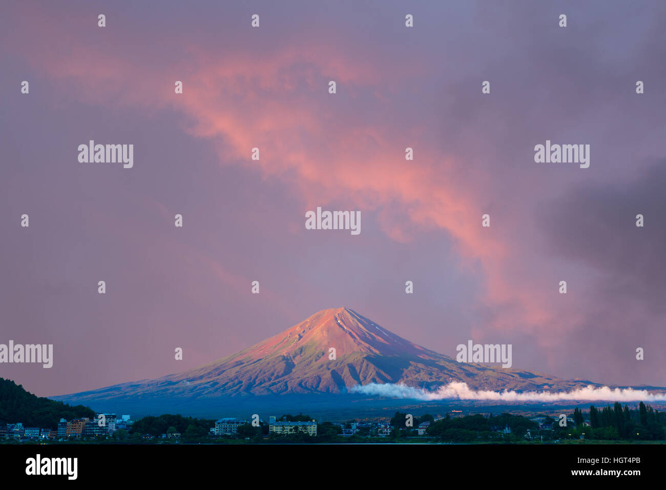 Beautiful red sunrise sky above the bright red volcanic cone of Mount Fuji with line of lake shore hotels in Kawaguchiko Stock Photo
