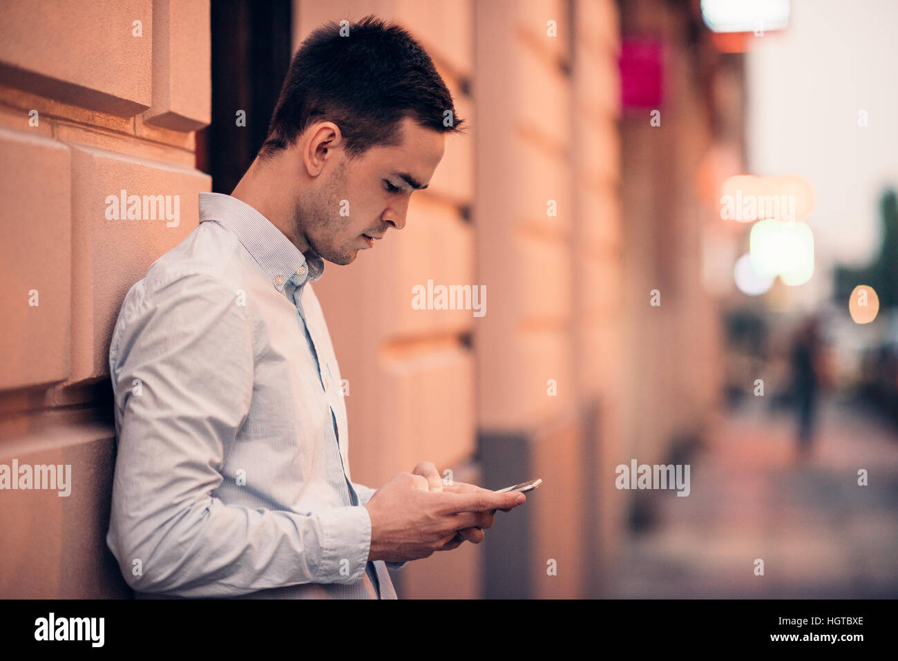 Handsome young man text messaging on a city street Stock Photo