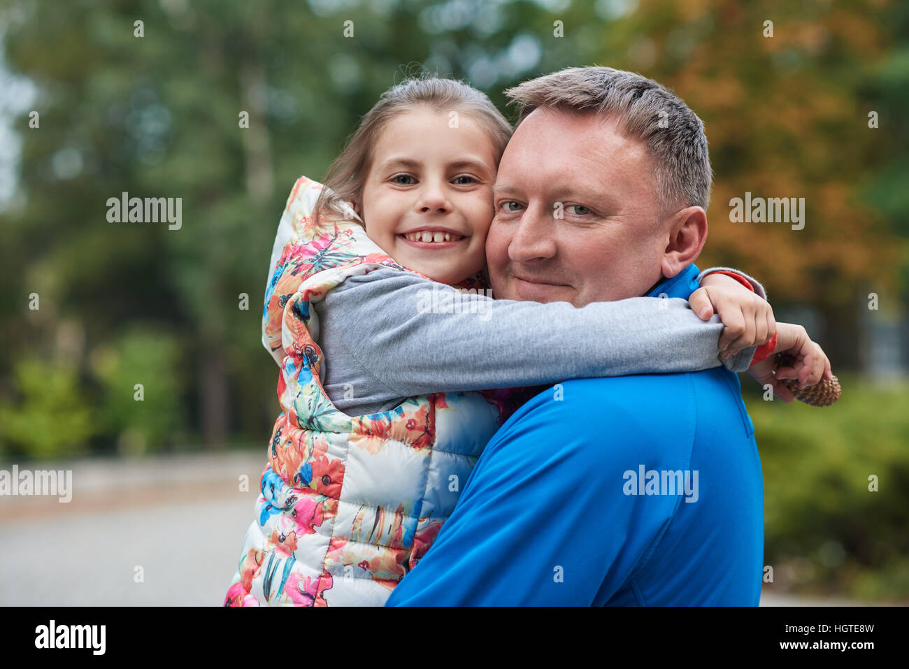 Smiling father and daughter hugging in a park Stock Photo