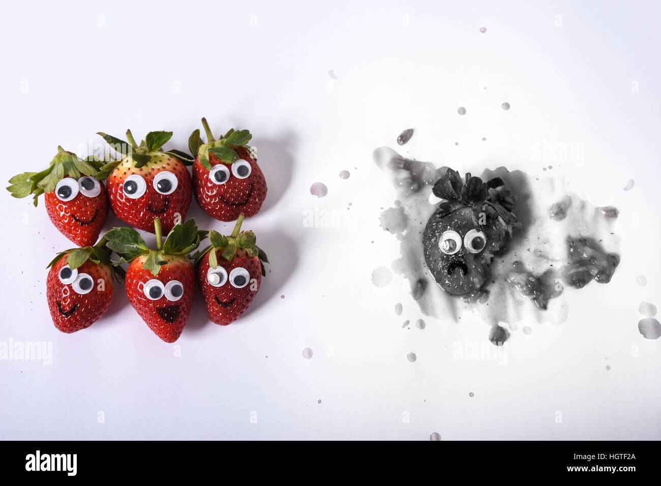 Strawberries with facial expressions showing that food shouldn't be wasted Stock Photo