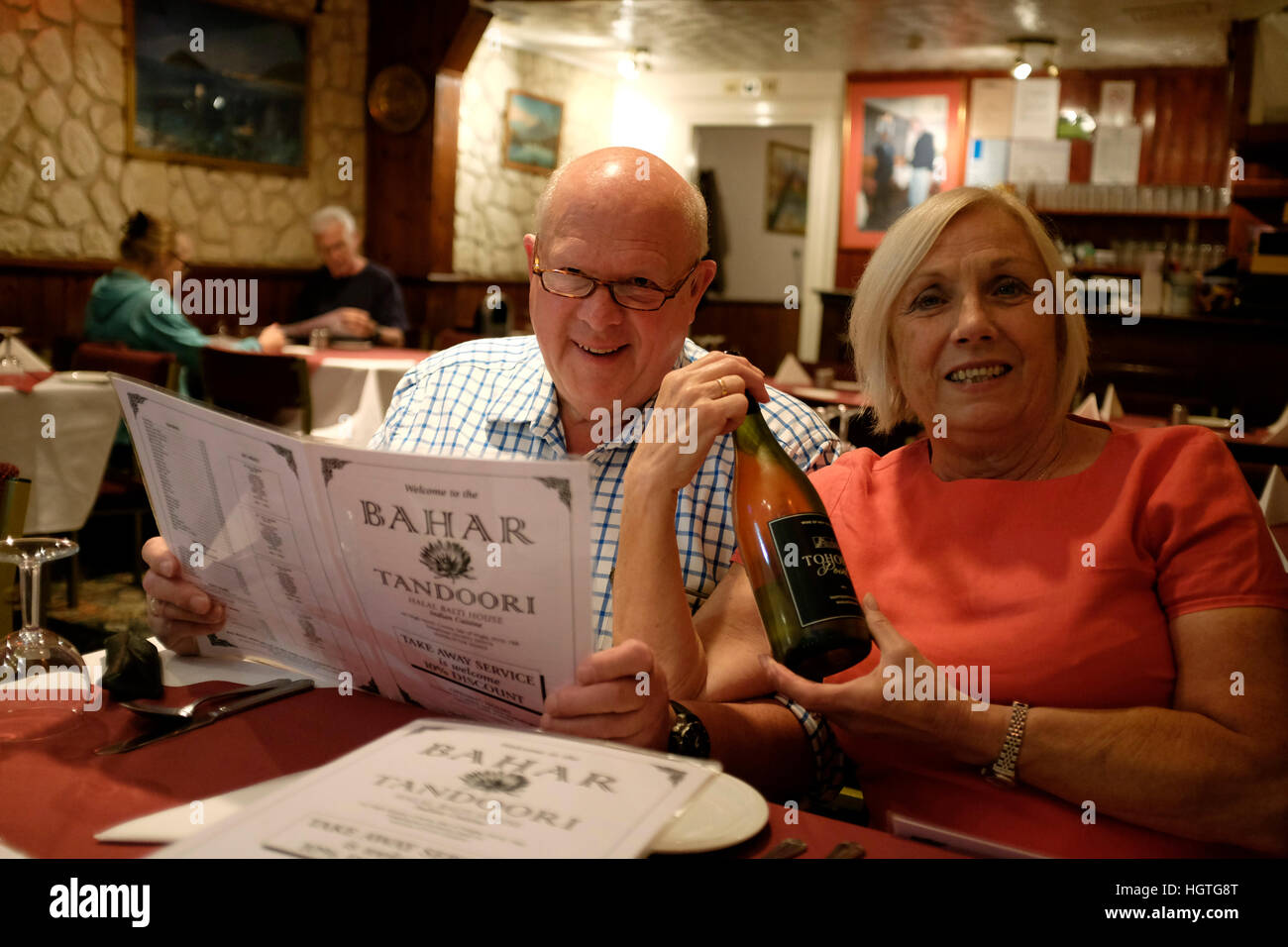 Couple looking at camera and menu at bring your own alcohol Indian