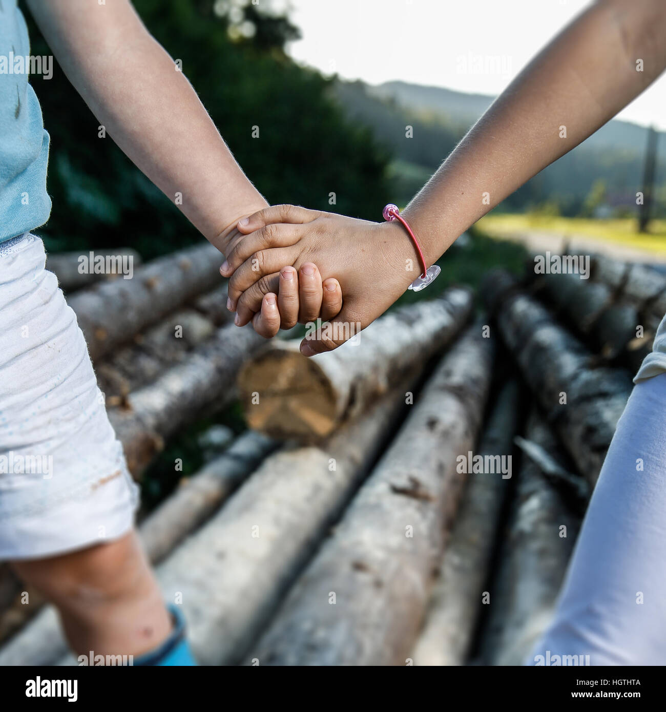 Friends holding hands, enjoying time together. Happy, carefree, outdoor countryside childhood, siblings love, companionship, family values concept. Stock Photo