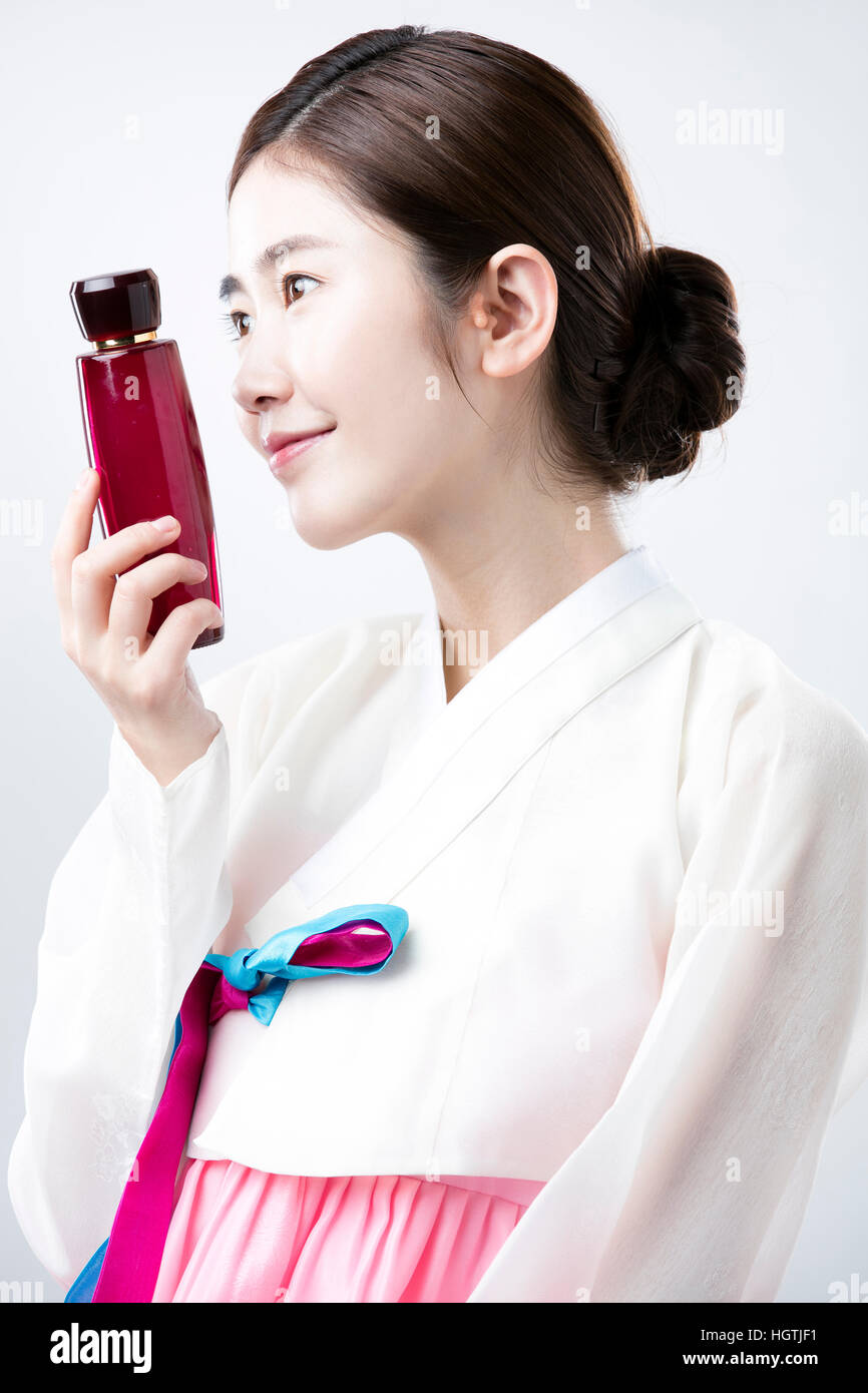 Side view portrait of young woman in traditional Korean clothes holding ...
